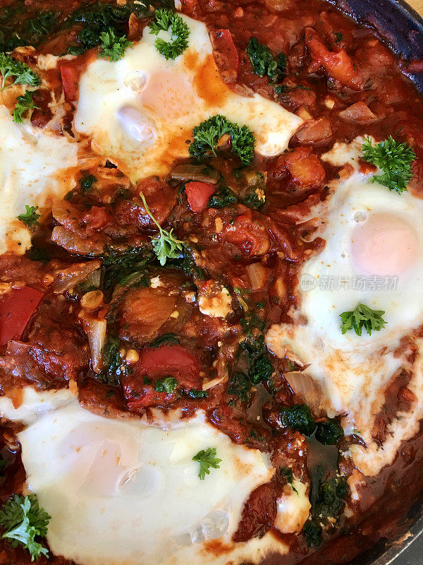 全框地中海健康早餐shakshouka / shakshuka / chakchouka在平底锅，鸡蛋煮在番茄酱，辣椒，洋葱，橄榄油和大蒜